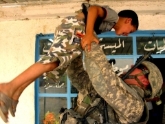 1st Lt. Tommy Ryan holds up a young boy during a patrol through the Taji Qada, northwest of Baghdad, July 12, 2008. Ryan serves as an infantry platoon leader with the 25th Infantry Division. Photo by Sgt. Brad Willeford, 2nd Stryker Brigade 25th Infantry Division.